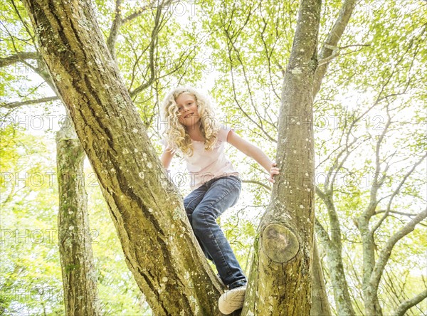 Girl (8-9) climbing tree