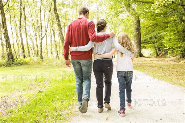 Daughter (8-9) with parents walking in park, rear view