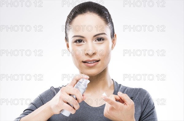 Young woman applying moisturizer