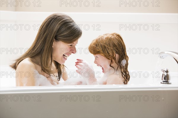 Mother and daughter (4-5) having bubble bath