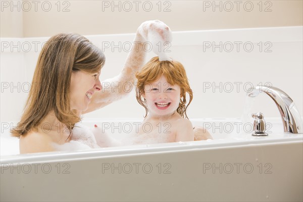 Mother and daughter (4-5) having bubble bath