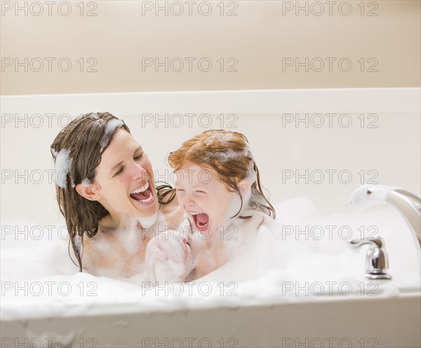 Mother and daughter (4-5) having bubble bath