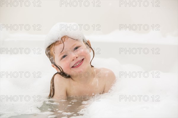 Smiling girl (4-5) having bubble bath