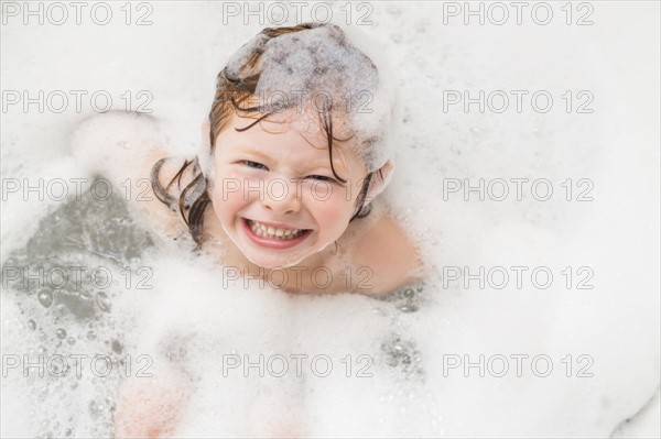 Smiling girl (4-5) having bubble bath