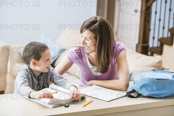 Mother helping son (6-7) doing homework