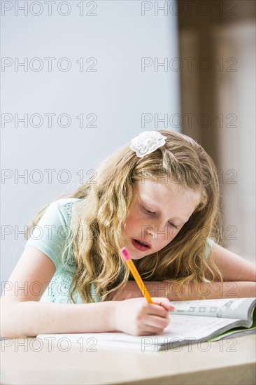 Blonde girl (8-9) doing homework at table