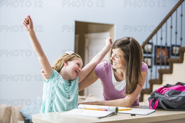 Mother and daughter (8-9) sitting at table doing homework