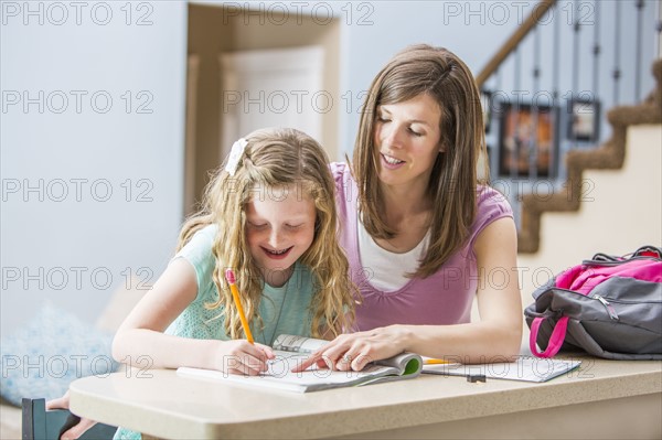 Mother and daughter (8-9) sitting at table doing homework