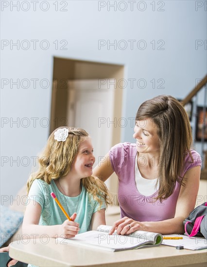 Mother and daughter (8-9) sitting at table doing homework