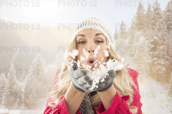 Young woman blowing snow off from hands