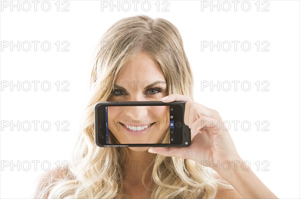 Young woman holding smart phone displaying smile against face