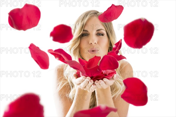 Young woman blowing rose petals off from hands