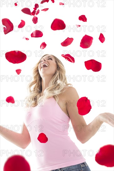 Young woman throwing up rose petals above head