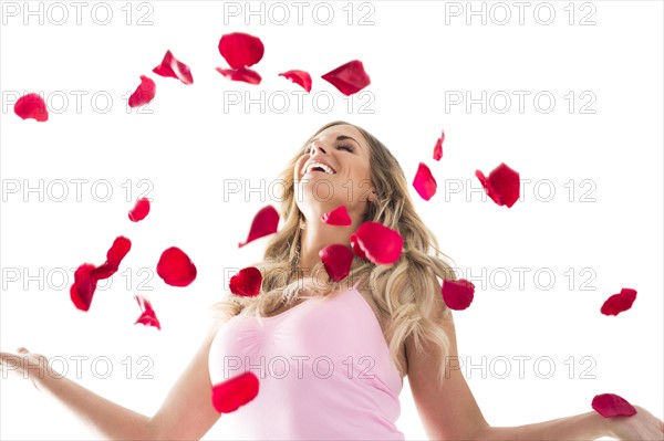 Young woman throwing up rose petals above head