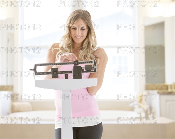 Young woman standing on weight scale in bathroom