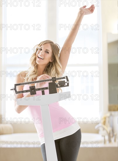Young woman standing on weight scale in bathroom