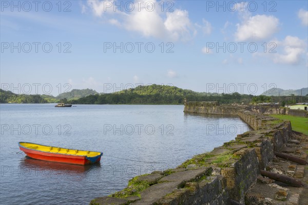 Boat on bay moored by stone wall