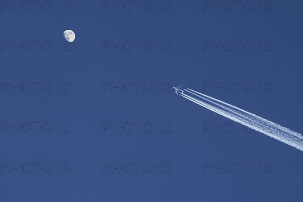 Airplane against blue sky with moon