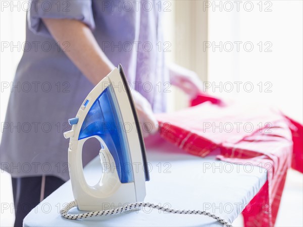 Mid-section of woman ironing shirt