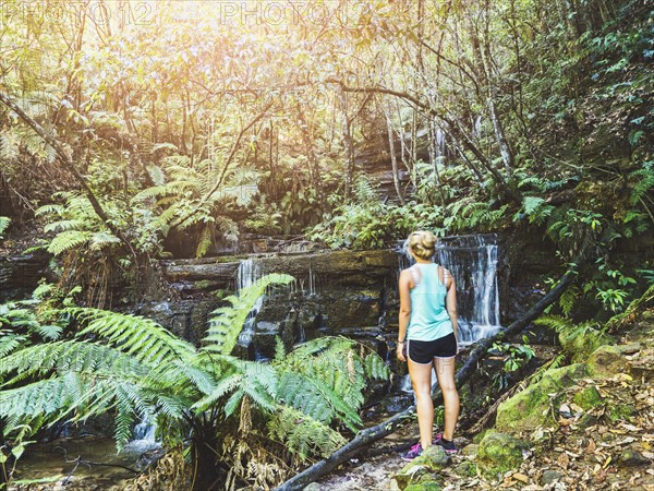 Young woman standing by waterfall in rainforest