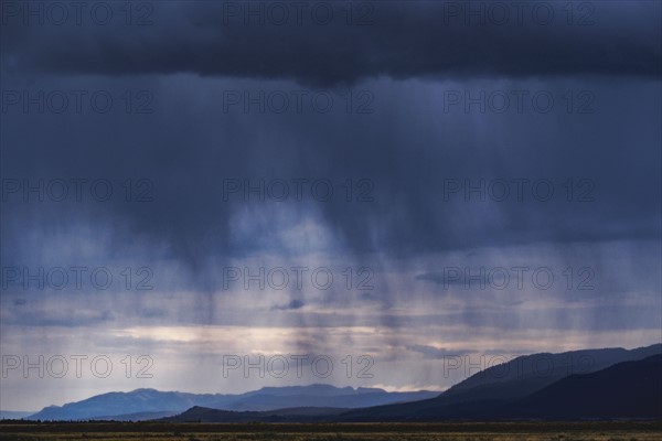 Storm clouds with rain over mountains