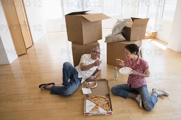 Couple eating pizza in new apartment.