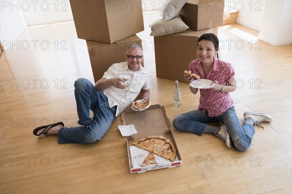 Couple eating pizza in new apartment.