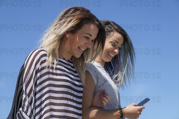 Young women laughing and looking at mobile phone.