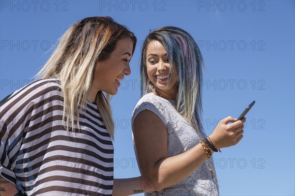 Young women laughing and holding mobile phone.