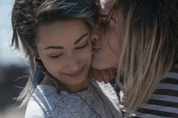 Young woman kissing friend on cheek.