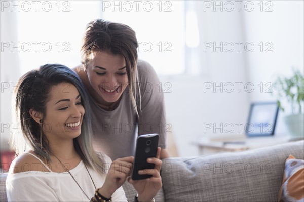 Young women using mobile phone at home.
