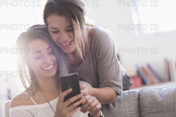 Young women using mobile phone at home.