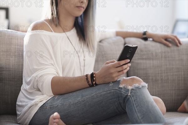 Young woman using mobile phone at home.