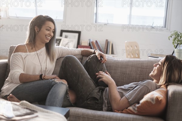 Young women talking on sofa.