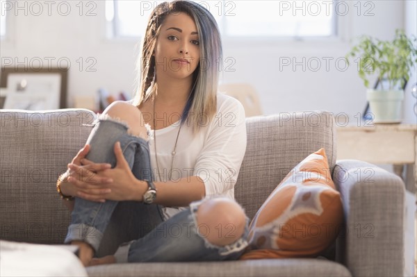 Confident young woman sitting on sofa.