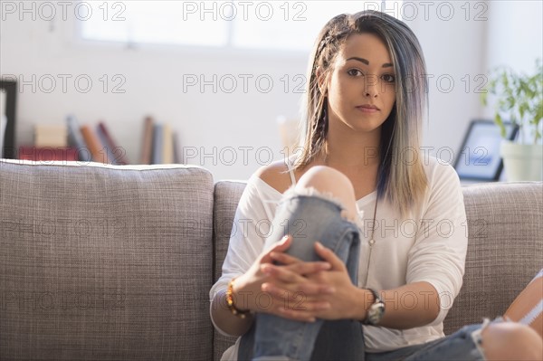 Confident young woman sitting on sofa.