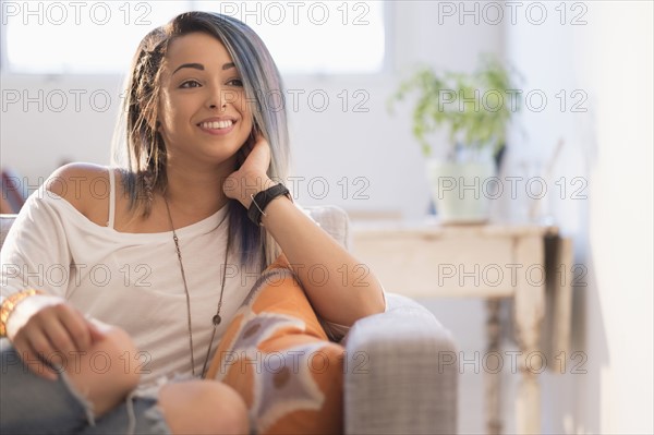 Smiling young woman sitting on sofa.