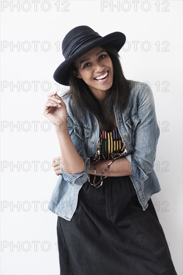 Studio portrait of mid adult woman in hat and denim jacket.