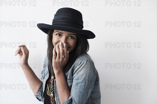 Studio portrait of mid adult woman in hat and denim jacket.