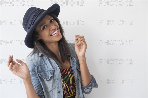 Studio portrait of mid adult woman in hat and denim jacket.