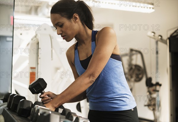 Woman choosing dumbbells for training.