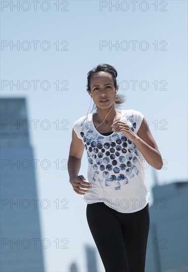 Front view of mid adult woman jogging in city.