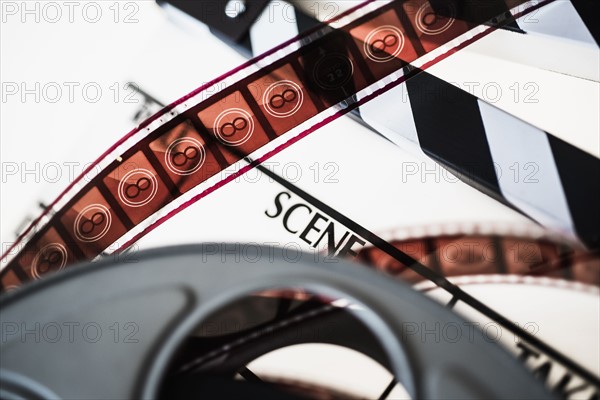 Close-up of film reel and slate against white background.