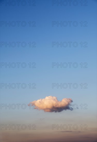 Single cloud on blue sky at sunset.