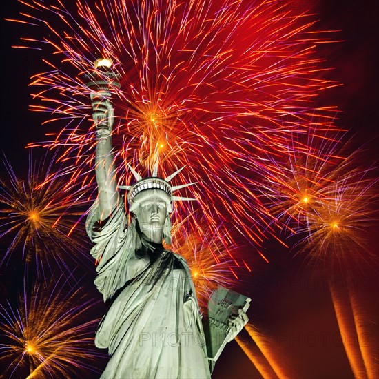 Firework display behind Statue of Liberty.