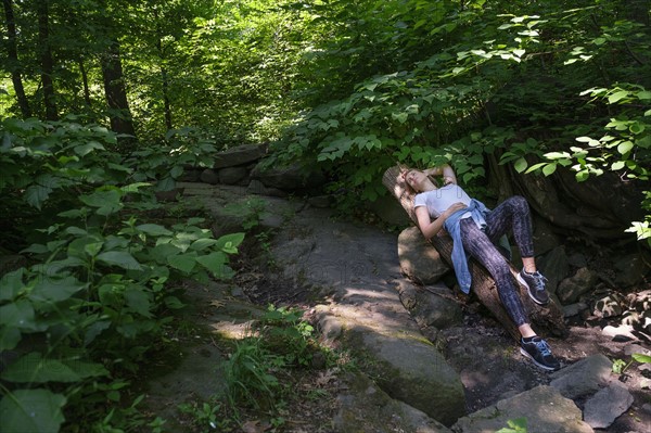 Woman lying on stone in forest.