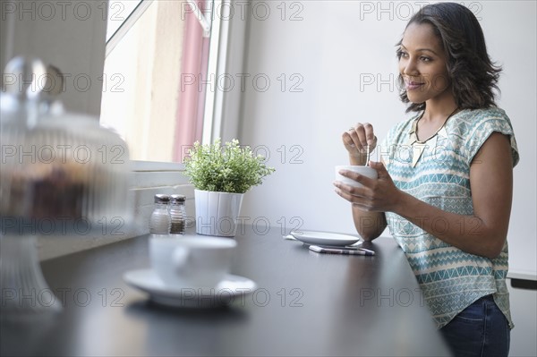 Woman drinking coffee by window.