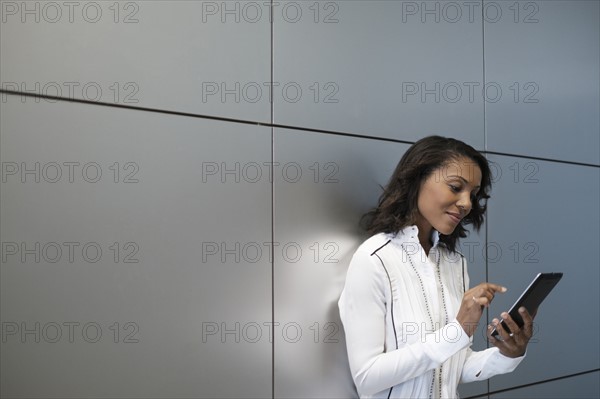 Woman standing by wall and using digital tablet.