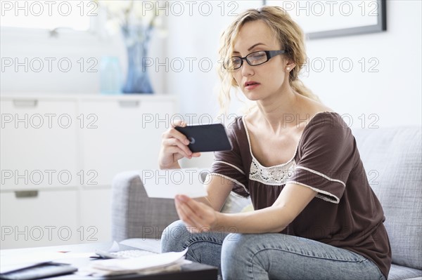 Woman taking picture of bill by cell phone.