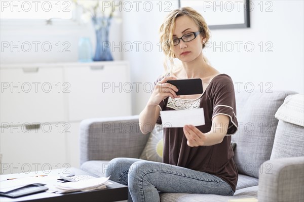 Woman taking picture of bill by cell phone.